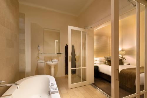 a bathroom with a bath tub and a bedroom at Hotel Frangos in Daylesford