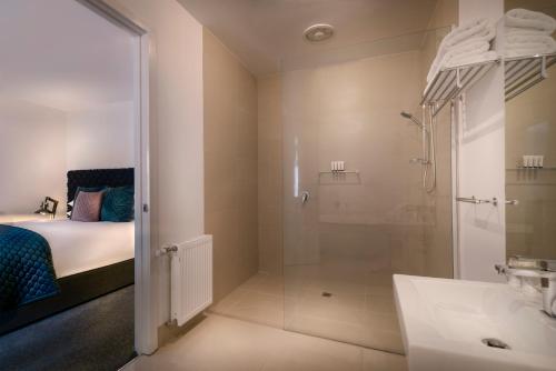 a bathroom with a shower and a bed and a sink at Hotel Frangos in Daylesford