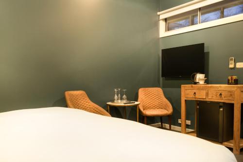 a bedroom with a bed and two chairs and a television at Hotel Frangos in Daylesford