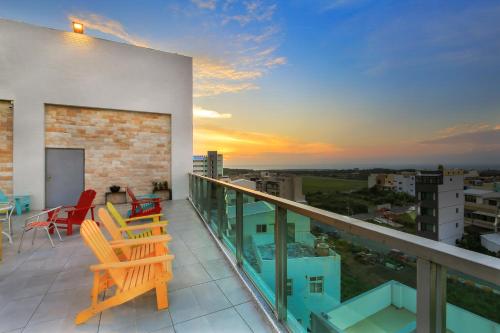 a balcony with chairs and a sunset in the background at A Homestay of the Yiwen Brigade in Magong