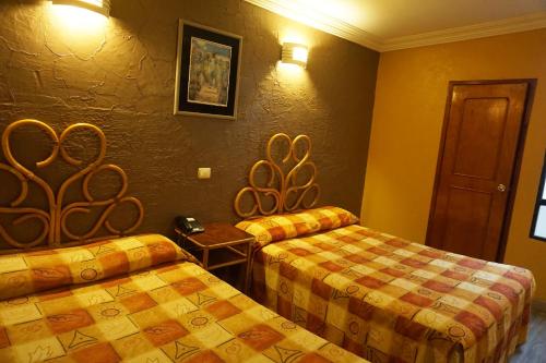 a hotel room with two beds and a table at Hotel Plaza Crystal in Xalapa