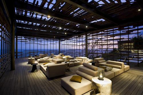 a large room with couches and tables in a building at Alila Villas Uluwatu in Uluwatu