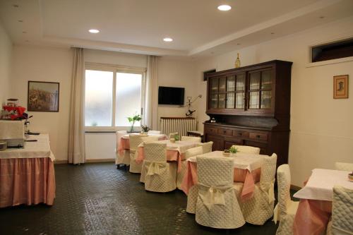 un restaurante con mesas y sillas blancas y una ventana en Hotel Persico, en Saluzzo