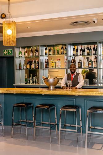 a bartender behind a bar with stools at Grand Daddy Boutique Hotel in Cape Town