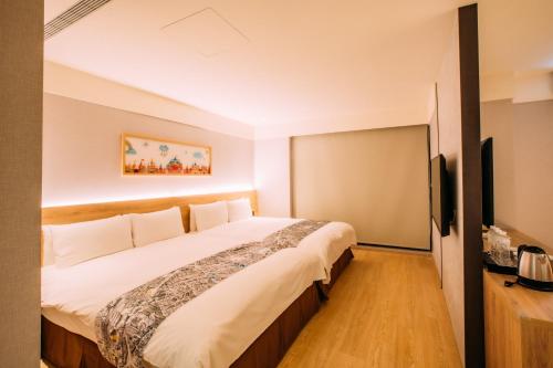 a bedroom with a large bed and a flat screen tv at Mega Hotel in Chiayi City