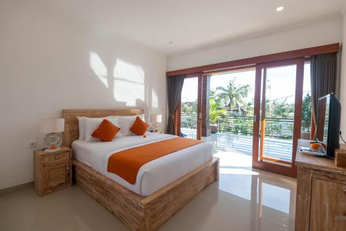 ウブドにあるVilla Semujan Ubud by Omkara Experienceのベッドとテレビとバルコニーのある寝室