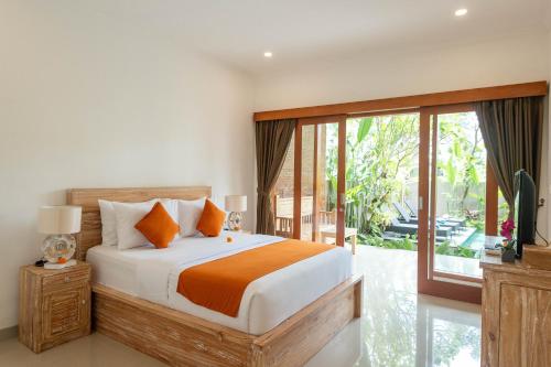sypialnia z łóżkiem i przesuwnymi szklanymi drzwiami w obiekcie Villa Semujan Ubud w mieście Ubud