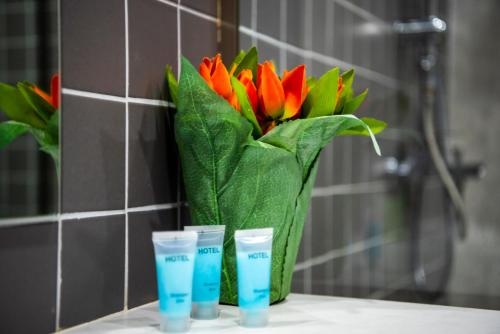 a vase of orange flowers and three cups on a counter at Sani Apart Hotel in Tbilisi City