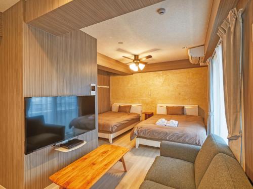 a room with two beds and a couch and a tv at Terrace Resort Mihama Chatan in Chatan