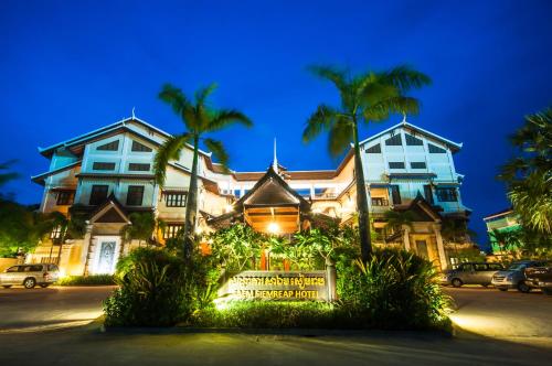 a large house with palm trees in front of it at Saem Siemreap Hotel in Siem Reap