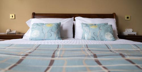 a bed with blue and white sheets and pillows at Arrochar Hotel 'A Bespoke Hotel' in Arrochar
