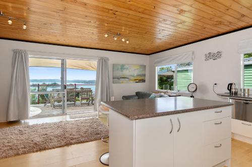 a kitchen with white cabinets and a view of the ocean at Bach and Relax - Oakura Holiday Home in Whangaruru North