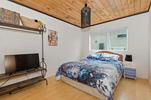 a bedroom with a bed and a flat screen tv at Bach and Relax - Oakura Holiday Home in Whangaruru North