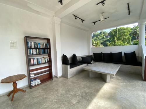a living room with a couch and a book shelf at Unawatuna Nor Lanka Hotel in Unawatuna