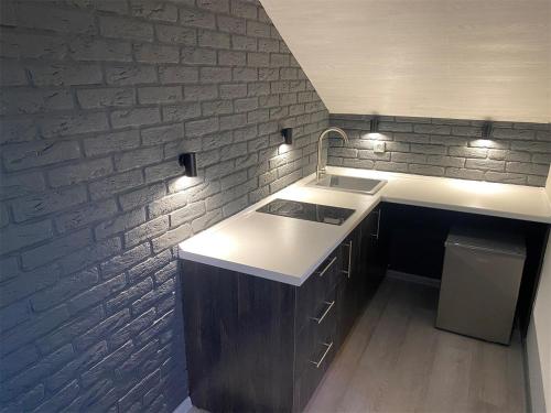 uma cozinha com um lavatório e uma parede de tijolos em Апарт-отель Attic em Zabaykal'sk