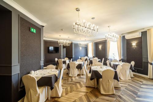 uma sala de banquetes com mesas e cadeiras brancas e lustres em Hotel Europa em Kalisz