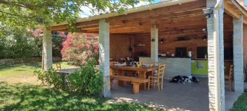 Una pérgola de madera con una mesa y un perro debajo. en Le Clos des Milans, en Rapale