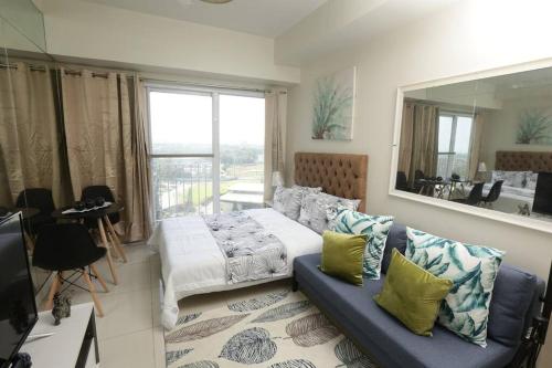 ein Schlafzimmer mit einem Bett, einer Couch und einem Spiegel in der Unterkunft A2J Executive Studio Suite near Skyranch & Malls Tagaytay in Tagaytay
