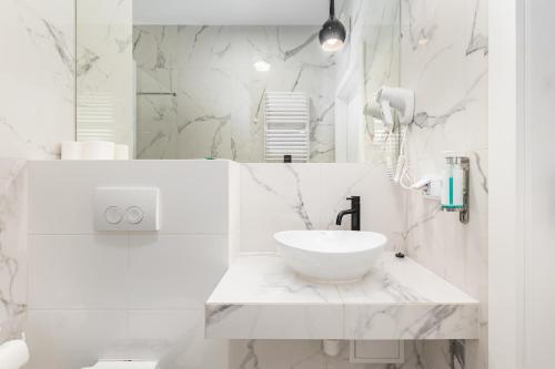 a white bathroom with a sink and a mirror at Prymasa Tysiąclecia 83A (C) by Homeprime in Warsaw