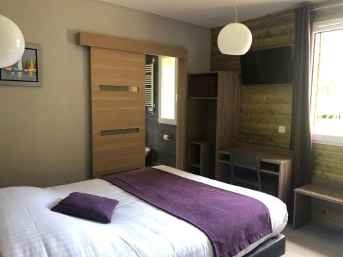 a bedroom with a large bed with a purple blanket at Logis Hotel Le Val Sarah in Bardouville