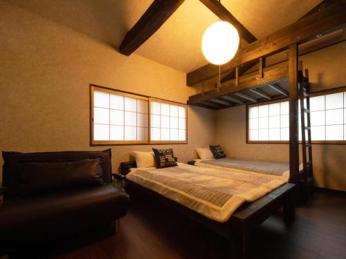 um quarto com um beliche e um sofá em Guest House Suzumeno Kakurembo em Monte Koya