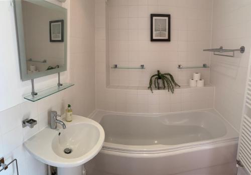 a white bathroom with a tub and a sink at Harrier Lodge in Cirencester