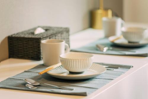 two cups and saucers on a table with silverware at 谷町君 HOTEL 恵美須町72 in Osaka