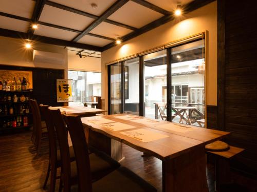 a dining room with a long wooden table and chairs at Guest House Suzumeno Kakurembo in Koyasan