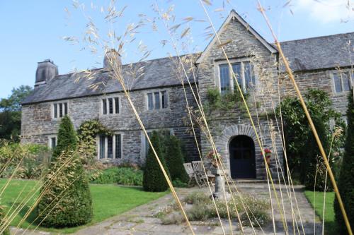 una antigua casa de piedra con un jardín delante de ella en Sortridge Manor - Leat House, en Tavistock