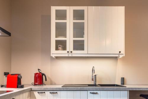 a kitchen with white cabinets and a sink at Oud Gemeentehuis in Poelkapelle