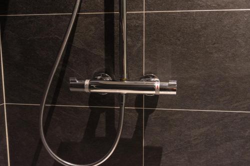 a shower with a hose attached to a tiled wall at Oud Gemeentehuis in Poelkapelle