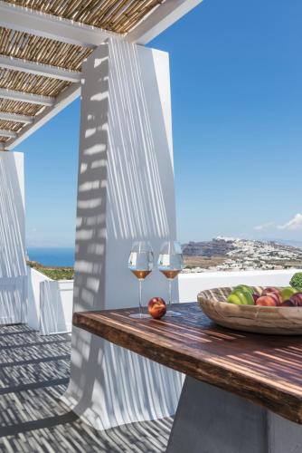 a table with two glasses of wine and a bowl of fruit at White & Co Exclusive Island Villas in Pirgos