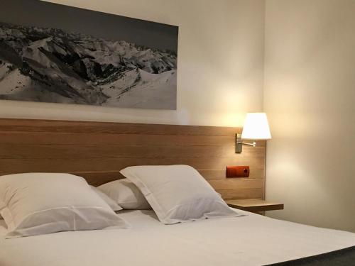 uma cama com duas almofadas brancas e uma fotografia na parede em Hotel Valdecoro em Potes