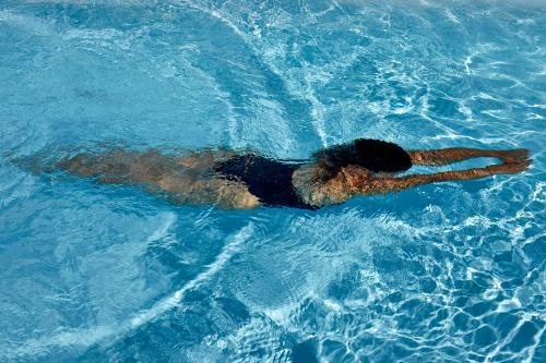 a man swimming in a pool of blue water at White & Co Exclusive Island Villas in Pirgos