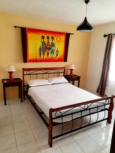 Un dormitorio con una cama con un cuadro en la pared. en Charming Apartment in Flic en Flac – 50m² with Pool, en Flic en Flac