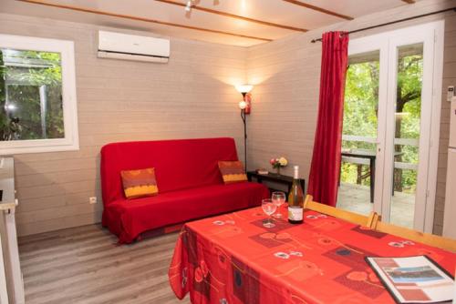 a living room with a red couch and a table at Le Mas de la Grenouillère in Joyeuse