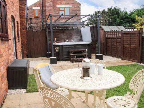 a patio with a table and chairs and a grill at The Little Beehive in Worcester