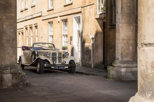 an old car parked on a street in an alley at Abbey Mews in Bath