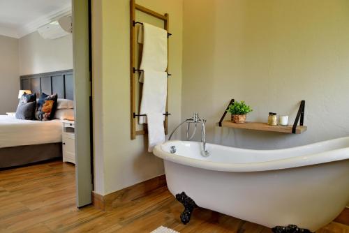 a white bath tub in a room with a bed at Thanda Manzi Country Hotel in Centurion