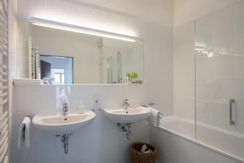 ein Badezimmer mit zwei Waschbecken, einer Badewanne und einem Spiegel in der Unterkunft Ferienwohnungen am Walmendingerhorn in Mittelberg