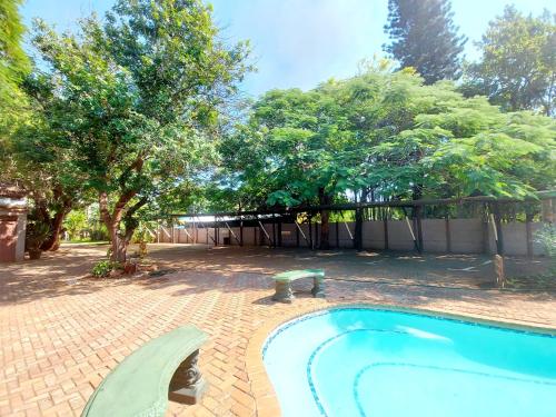 a swimming pool in a yard with trees and a fence at Sundown Lodge in Komatipoort