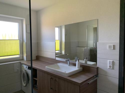 La salle de bains est pourvue d'un lavabo et d'un miroir. dans l'établissement Exklusive Wohnung mit Brettachblick, à Rot am See