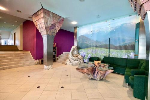 a lobby with a green couch and a large window at Hills View Apartment in Donovaly