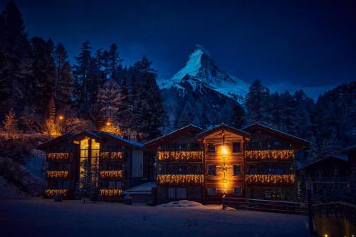 a lodge with a mountain in the background at night at Matthiol Boutique Hotel in Zermatt