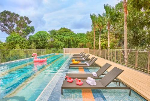 a swimming pool with chaise lounges and inflatables at lyf one-north Singapore in Singapore