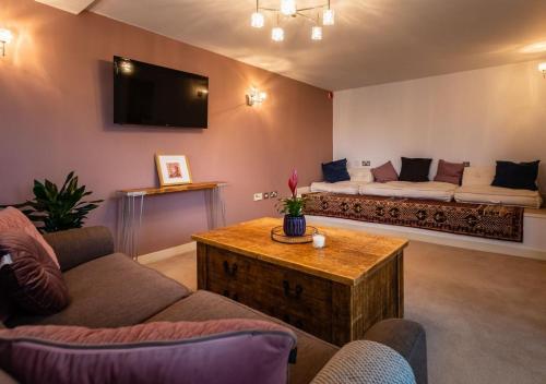a living room with a couch and a table at Lux Duplex Apartment 19th Century Chapel Wakefield Centre in Wakefield