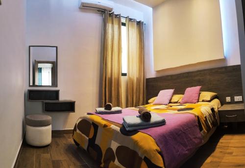 - une chambre dotée d'un grand lit avec des draps roses et jaunes dans l'établissement Diamonds Luxury Apartments, à Marsalforn
