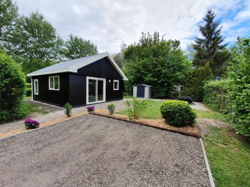 a black tiny house with a gravel driveway at Camping Alkenhaer Appelscha Bungalow in Appelscha