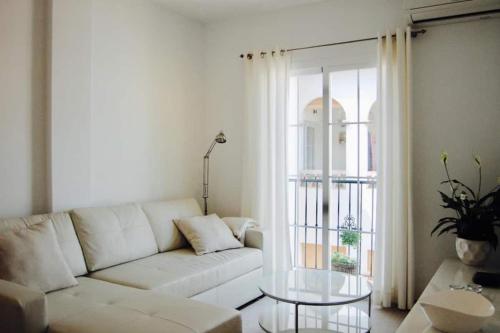 a living room with a white couch and a glass table at Fantastic 1 bedroom apartment in the centre of Nerja in Nerja