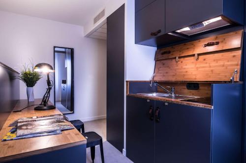 a kitchen with blue cabinets and a sink and a counter at Best Western Plus Suitcase Paris La Défense in Bois-Colombes